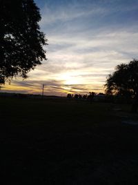 Silhouette trees on field against sky during sunset