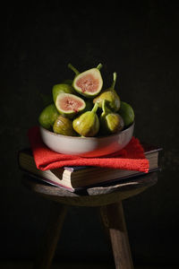 Ripe figs heap on book and old wooden stool in studio