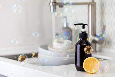 Bottle with eco friendly dishwashing detergent with lemon on the background of a sink with dishes 