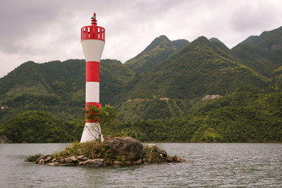 Lighthouse amidst rocks and mountains against sky