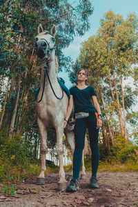 Young woman standing with horse against sky