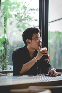 Young man using mobile phone while drinking coffee at restaurant