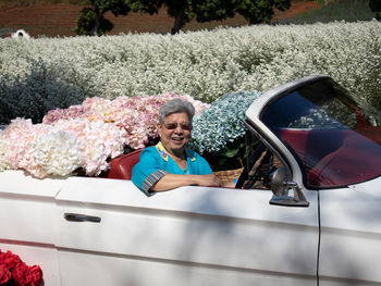 Asian old elderly elder woman senior riding retro classic car with hydrangea flower in cutter garden