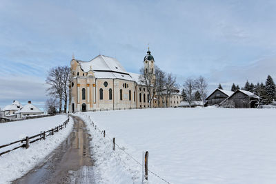 Empty road amidst snow covered field leading towards wies church at winter