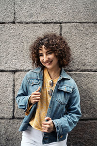 Young woman smiling while standing against wall