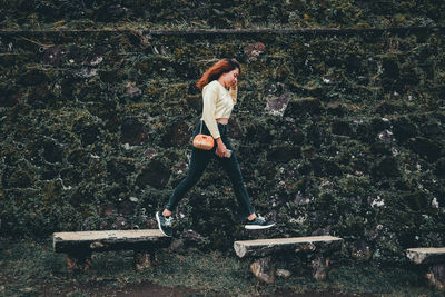 Full length of woman standing on bench