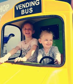 Portrait of smiling girl sitting on yellow car