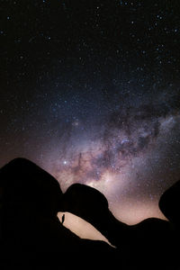 Low angle view of silhouette mountain against sky at night