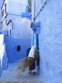 Rear view of man in alley amidst buildings