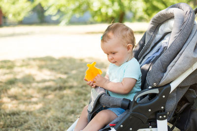Baby girl sitting in stroller at park