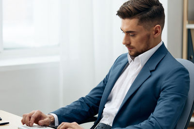 Young businessman sitting by desk at office