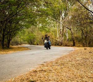 Man riding bicycle on road in forest