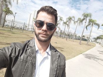 Portrait of young man wearing sunglasses against sky