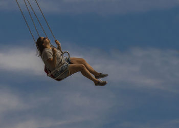 Low angle view of woman jumping against sky