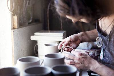 Cropped image of artist checking mug at workshop