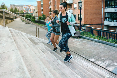 Young women friends training running up stairs in town
