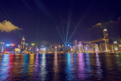 Illuminated city by buildings against sky at night