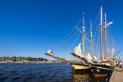 Sailboat sailing on sea against clear blue sky