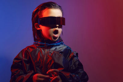 Portrait cyberpunk boy child in vr glasses in blue and red tones. game, virtual reality