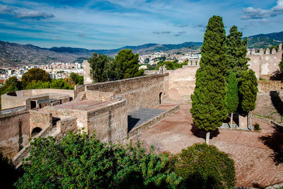 Trees on fort at gibralfaro against cloudy sky