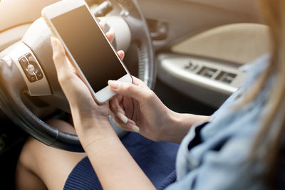 Midsection of woman using smart phone while sitting in car