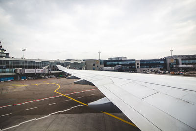 Airplane on airport runway against sky in city