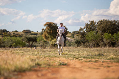 Man riding horse on field against sky