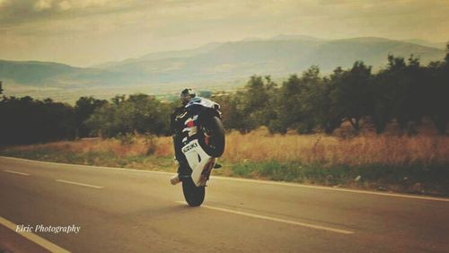 Rear view of man riding motorcycle on country road