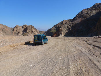 Car on desert against blue sky