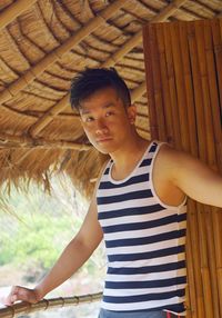 Portrait of young man standing in thatched roof