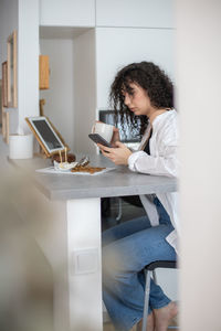 Young woman using mobile phone in kitchen