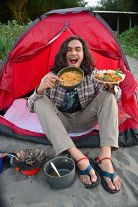 Full length of happy woman sitting in tent