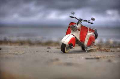 Tilt-shift on old motor scooter parked on road against cloudy sky