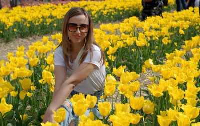 Young woman standing by yellow flowers in field