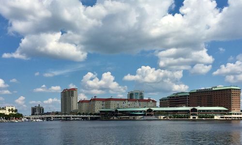 Buildings by river against sky