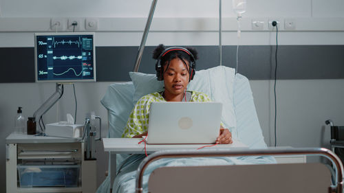 Patient using laptop while sitting on bed at hospital