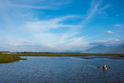 People in lake against sky