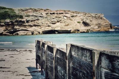 Wooden fence at beach during sunny day