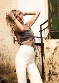 Portrait of young woman standing against wall