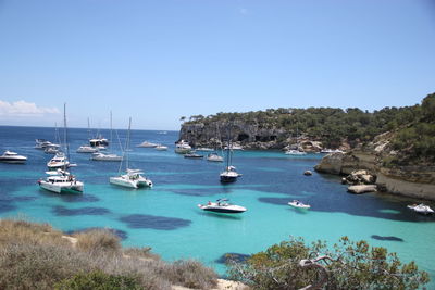 Boats moored in sea against clear blue sky