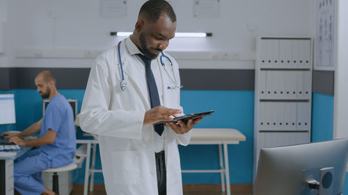 Smiling doctor using digital tablet at hospital