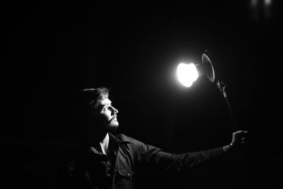 Man holding illuminated lighting equipment against black background