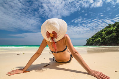 Woman sitting at beach against sky