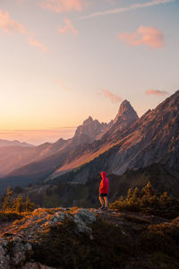 Rear view of man walking on mountain against sky during sunset