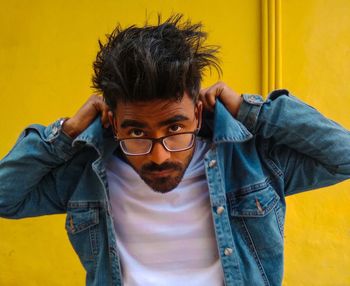 Portrait of young man standing against yellow wall