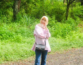 Portrait of a smiling young woman standing on grass