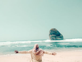 Rear view of person at beach against clear sky