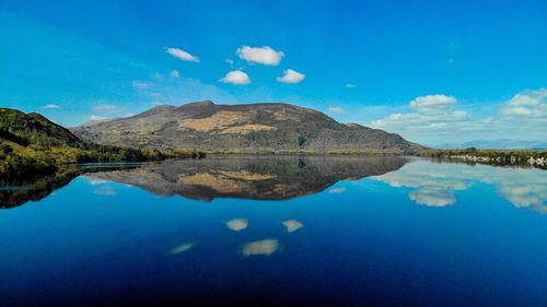 Scenic view of lake and mountains against blue sky