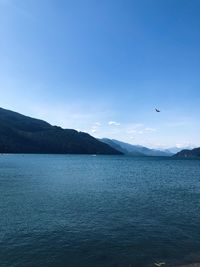 Scenic view of sea and mountains against blue sky