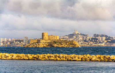 Scenic view of sea by buildings against sky